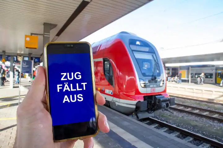 Symbolbild GDL-Streik (Gewerkschaft deutscher Lokomotivführer): Nahaufnahme von einem Smartphone vor einem Regionalzug