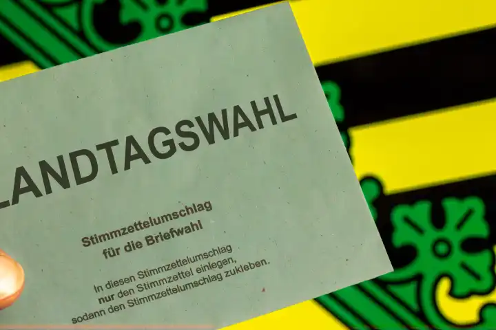 Symbolbild Landtagswahl in Sachsen: Umschlag zur Briefwahl vor dem Wappen von Sachsen. Im September 2024 findet die nächste Landtagswahl statt