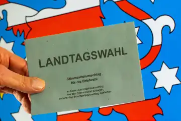 Symbolbild Landtagswahl in Thüringen: Umschlag zur Briefwahl vor dem Wappen von Thüringen. Im September 2024 findet die nächste Landtagswahl statt