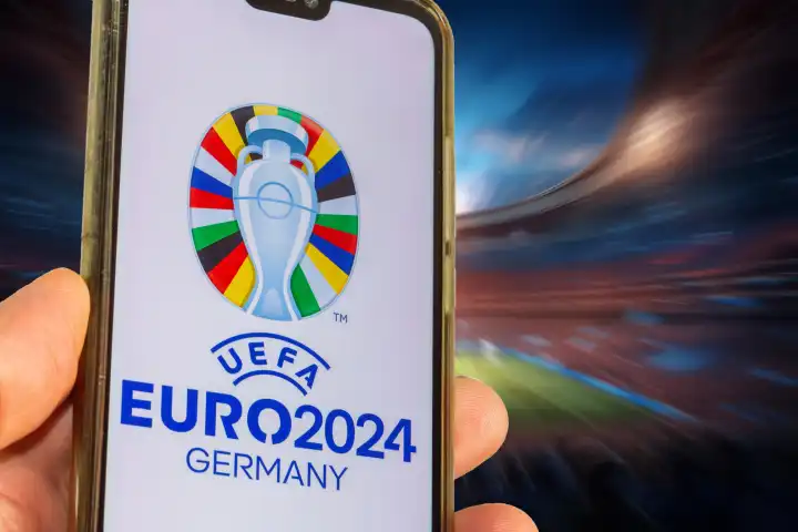 Symbolbild UEFA-EURO 2024: Smartphone mit dem Logo der EURO vor einem vollen Stadion