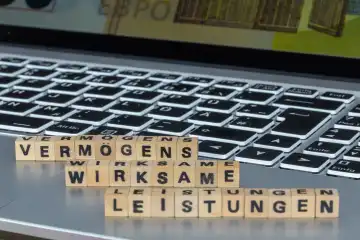 Symbolbild der vermögenswirksamen Leistungen (Deutschland): Das Wort VERMÖGENSWIRKSAME LEISTUNGEN ist auf einem Laptop mit Buchstabenwürfeln geschrieben