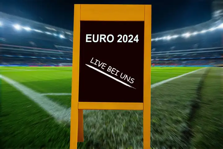 Symbolbild Public Viewing bei der UEFA EURO 2024: Aufsteller mit der Aufschrift EURO 2024 LIVE BEI UNS in einem Fußballstadion (Composing)