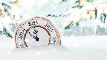 Vintage Uhr im Schnee und zeigt auf das neue Jahr 2024. Schöner Winterhintergrund mit Tannen und Lichtern. Neujahr und Weihnachten Countdown, kreative Idee.
