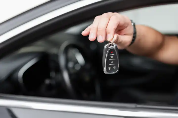 The male driver sits in the car and gives the keys. Rent a Car.