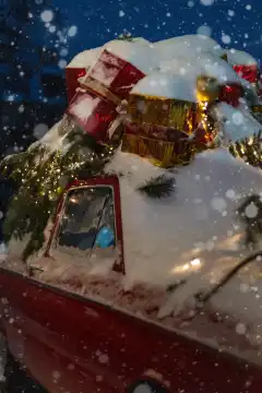 Schöne Retro Vintage rotes Auto mit Spielzeug, Weihnachtsbaum, Kugeln und Lichter mit Schnee in der Nacht. Heiligabend Karte