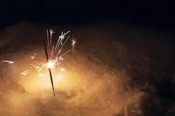Festive sparklers burn on the snow at night. New Year and Christmas card