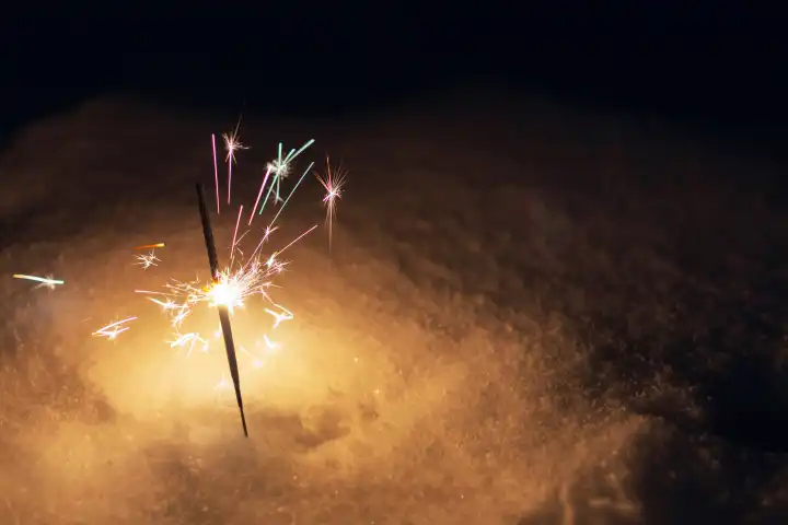 Festive sparklers burn on the snow at night. New Year and Christmas card