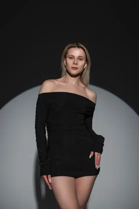 Stylish schöne Mode Mädchen in einem modischen schwarzen sexy Kleid auf einem dunklen Hintergrund im Studio. Frische Dame