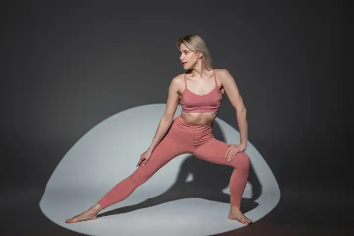 Athletische schöne Mode Frau mit einem gesunden Körper fit in Sportkleidung mit einem Top und Leggings macht eine Übung im Studio. Yoga