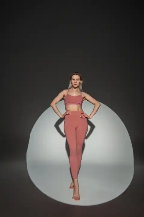 Mode schöne stilvolle Yoga Frau mit fit Körper in Top mit Leggings posiert im Studio auf einem dunklen Hintergrund