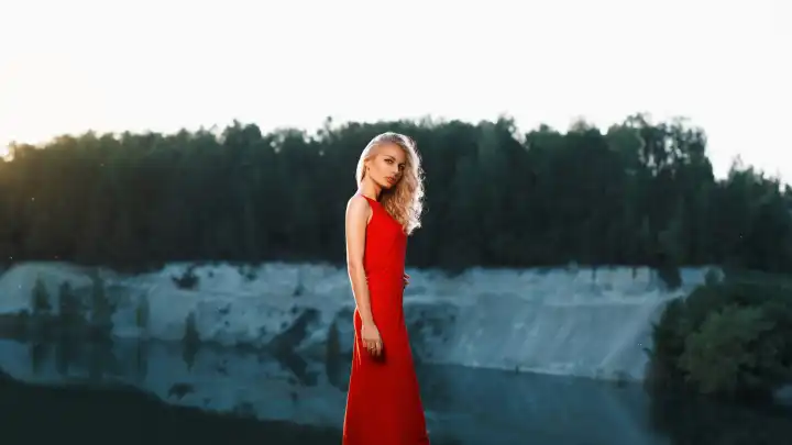 Porträt einer schönen Frau in einem roten Kleid auf einem Berg in der Nähe des Flusses