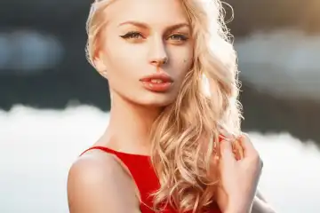 Close-up portrait of a beautiful woman with red dress on the background of the sea. Sunset light