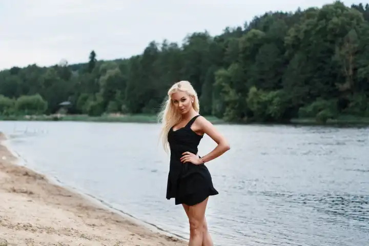 Schönes Mädchen in schwarzem Kleid am Flussufer