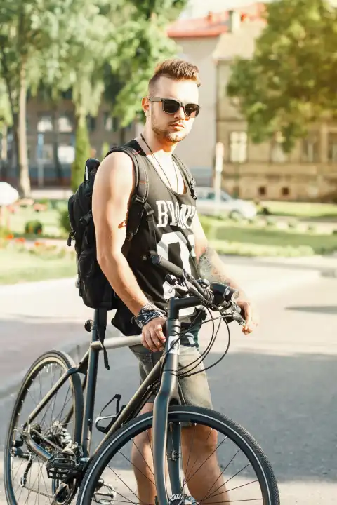 Porträt eines jungen Mannes mit einem Fahrrad auf der Straße. Schwarzes T-shirt mit Druck 23