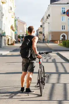 Young guy with a bicycle goes along the street.