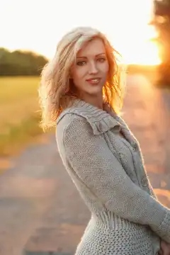Pretty woman in knitted sweater at sunset on nature