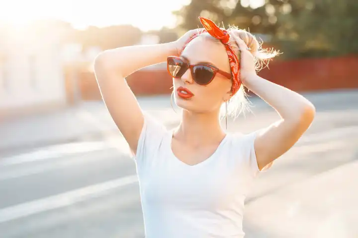 Schöne Hipster-Frau mit roten Lippen und Sonnenbrille stehend auf der Straße bei Sonnenuntergang