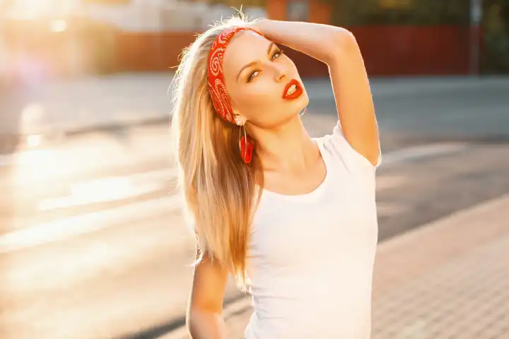 Porträt eines hübschen Hipster-Mädchens mit roten Lippen im weißen T-Shirt auf der Straße bei Sonnenuntergang