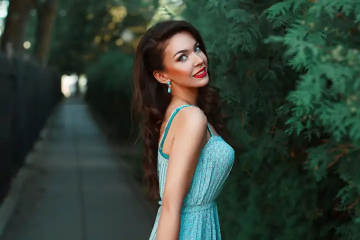 Modeporträt eines schönen lächelnden Mädchens in einem türkisfarbenen Kleid im Park.