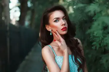 Fashion portrait of a beautiful woman in a turquoise dress in the park.
