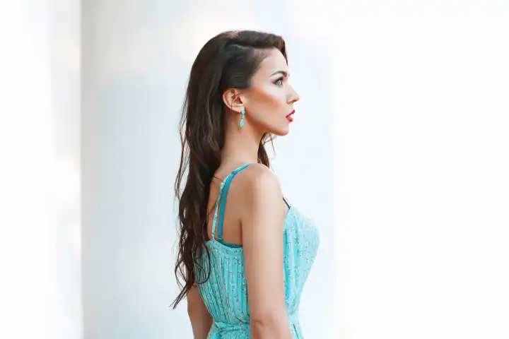 Porträt einer jungen hübschen Frau mit türkisfarbenem Kleid auf weißem Hintergrund. Profil Gesicht