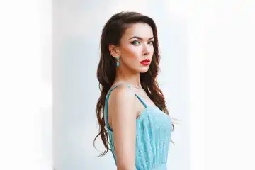 Portrait of beautiful woman with red lips and a turquoise dress on a white background