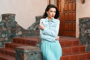 Young beautiful woman in denim dress standing and twisting stone steps near the house.