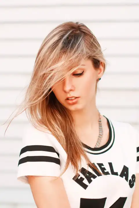 Porträt eines schönen Hipster-Mädchens an einer weißen Holzwand. Haare im Wind