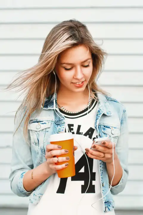 Schönes glückliches Hipster-Mädchen hört Musik am Telefon und trinkt Kaffee.
