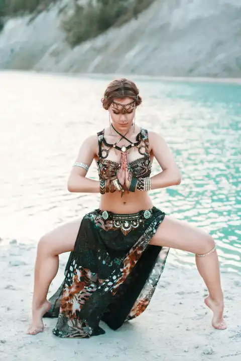 Schönes Mädchen in Stammes-Fusion-Kostüm in einer Pose an den Ufern des Strandes stehen, Hintergrund des blauen Meeres.