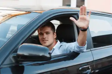 A young man in a car stuck his hand out the window. Man approves