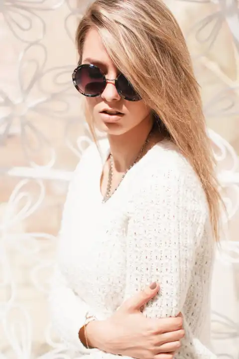Outdoor fashion portrait of young pretty woman with round sunglasses in summer sunny day on street.