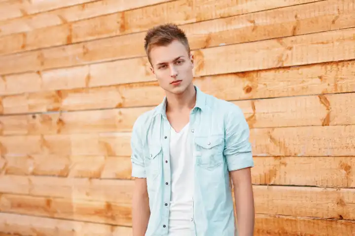Junger gutaussehender Mann in einem Jeanskleid in der Nähe der Holzwand