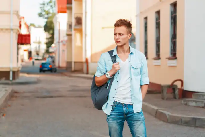 Junger hübscher Mann mit Rucksack in Jeanshemd und Jeanskleidung auf Reisen.