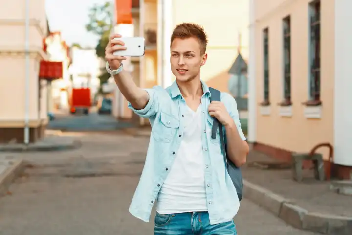 Moderne touristYoung Junge in der Nähe einer Holzwand tun ein Selbstporträt auf dem Telefon auf dem Hintergrund der Stadt
