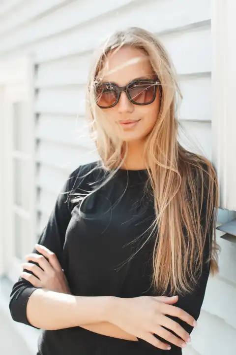 Stilvolles schönes Mädchen mit Sonnenbrille in der Nähe einer Holzwand