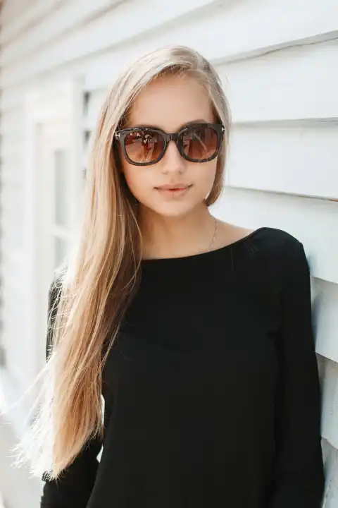Hübsche Frau mit Sonnenbrille in der Nähe einer Holzwand