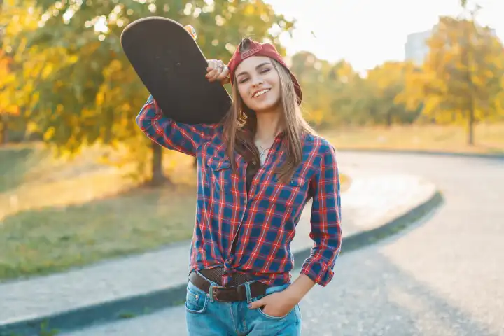 Porträt eines hübschen Mädchens mit einem Skateboard in der Hand, im Freien