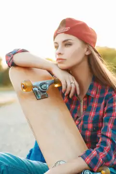 Pretty woman with skateboard in autumn day. On the background of a beautiful sunset.