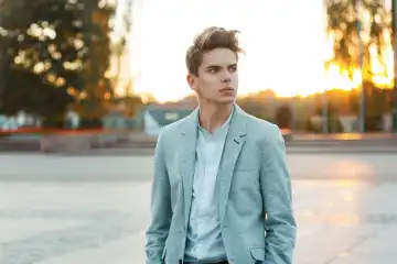 Handsome young businessman in a jacket and shirt outdoors at sunset
