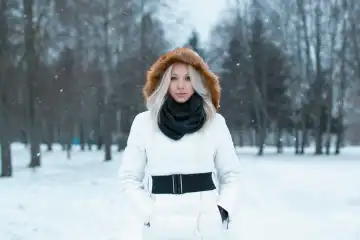 Beautiful girl  in a winter jacket stands in the park