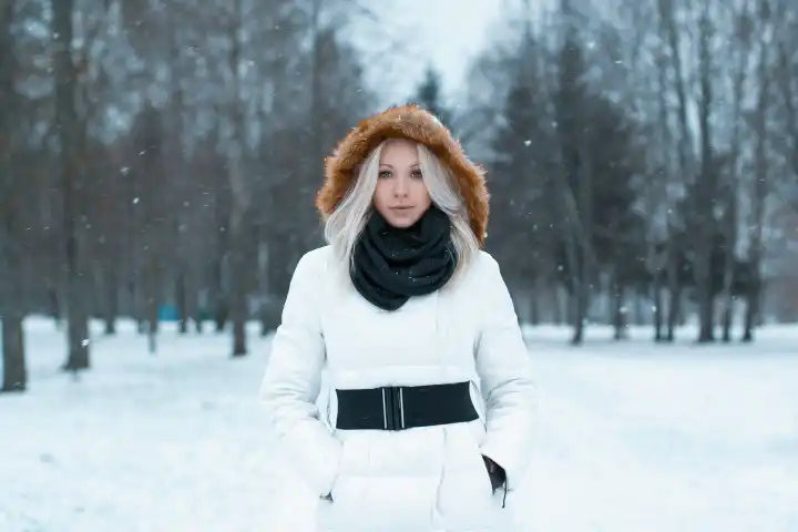 Schönes Mädchen in einer Winterjacke steht im Park