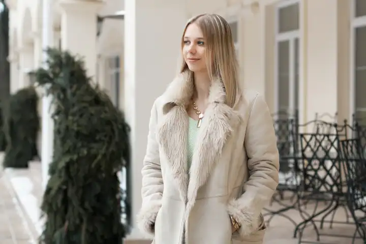 Schönes Mädchen in der Winterjacke steht in der Nähe des Gebäudes