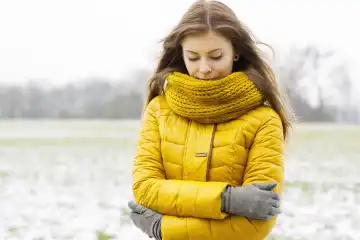 Pretty woman in a yellow knit scarf and yellow jacket. Outdoors portrait in the park.