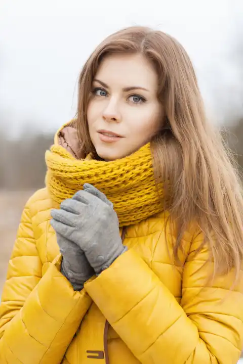 Hübsche Frau mit einem gelben Strickschal.  Warme Hände.