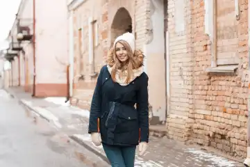 Beautiful woman standing near old brick wall. Old residential homes in the city center. Outdoors in winter.