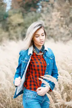 Beautiful stylish girl in denim jacket, checkered red shirt and blue jeans.
