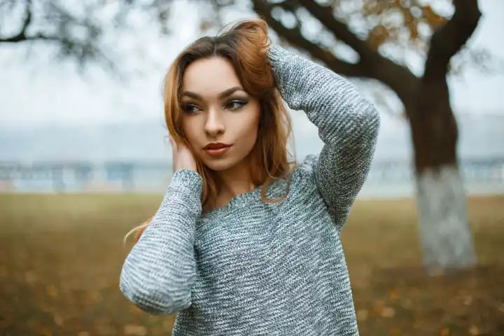 Young beautiful girl in a knitted sweater in a foggy autumn day