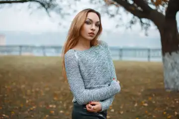 Stylish girl in a knitted sweater in a foggy autumn day