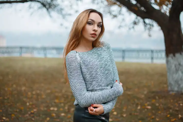 Stylish girl in a knitted sweater in a foggy autumn day